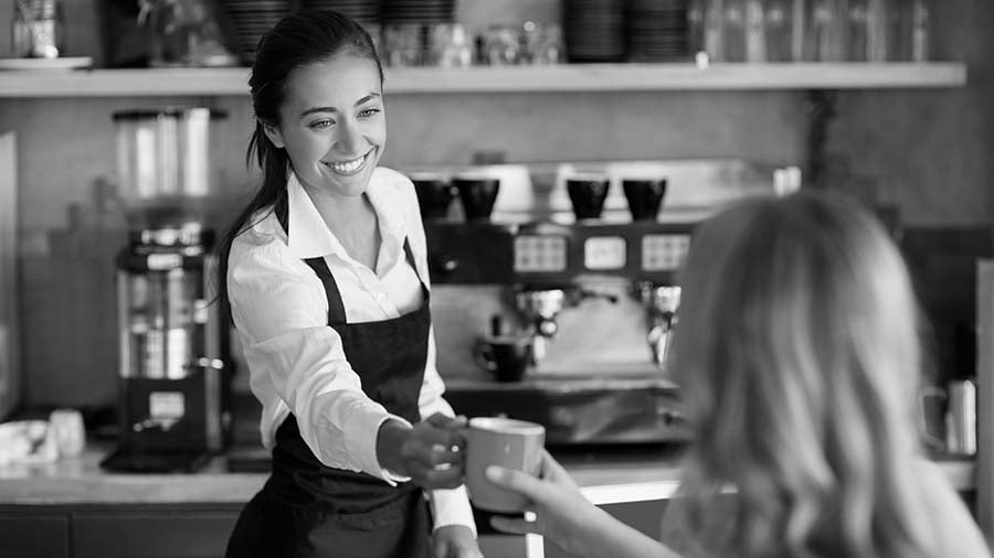 Cafe waitress handing over coffee mug to patron