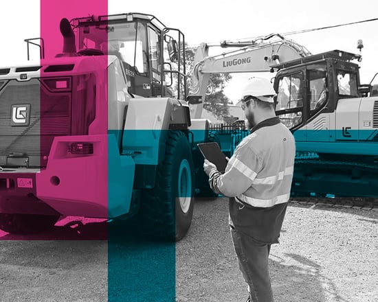 Tradesman inspecting parked excavator with ipad