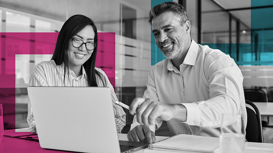 Two people smiling at laptop in office